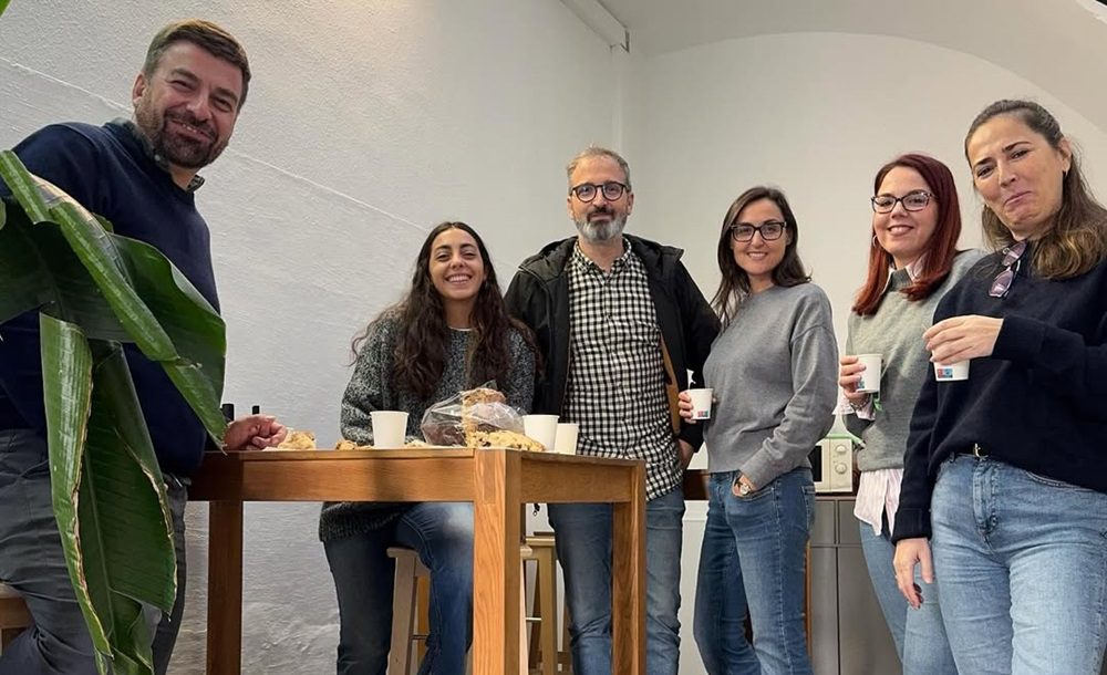 Personas conversando y colaborando en un espacio de coworking moderno y luminoso, compartiendo experiencias de trabajo.