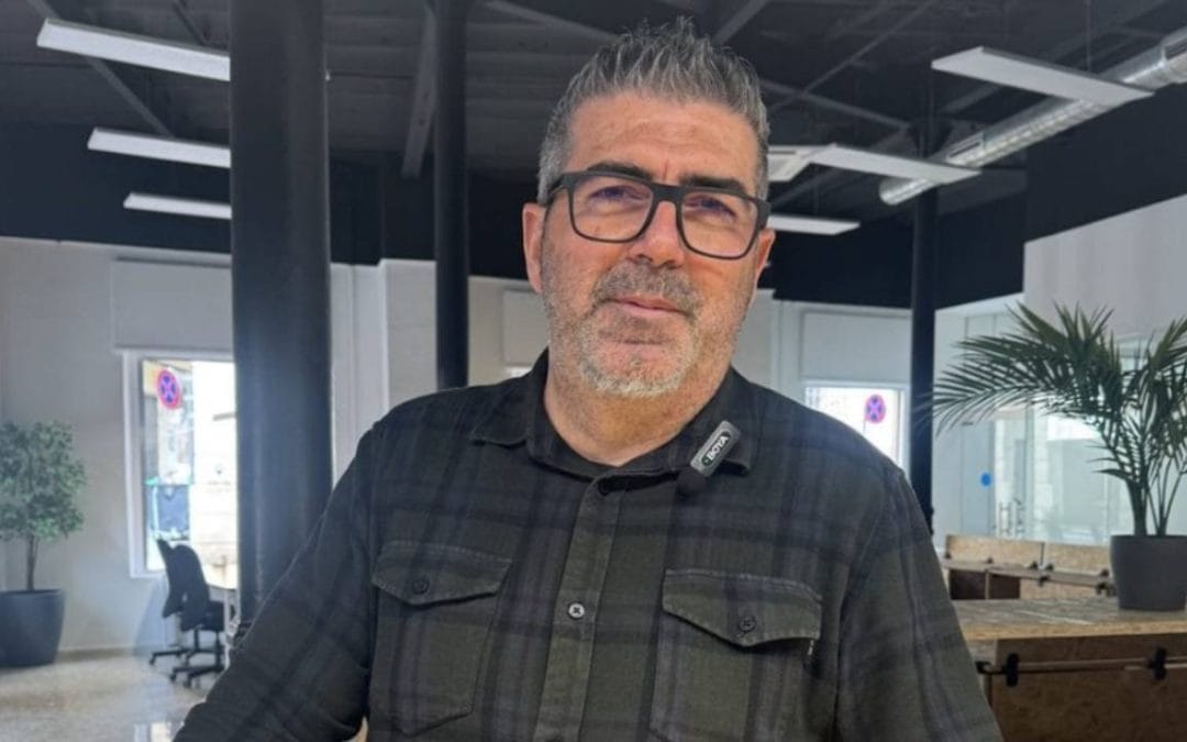 Dos personas conversando en un espacio de coworking moderno con mesas y ordenadores portátiles.