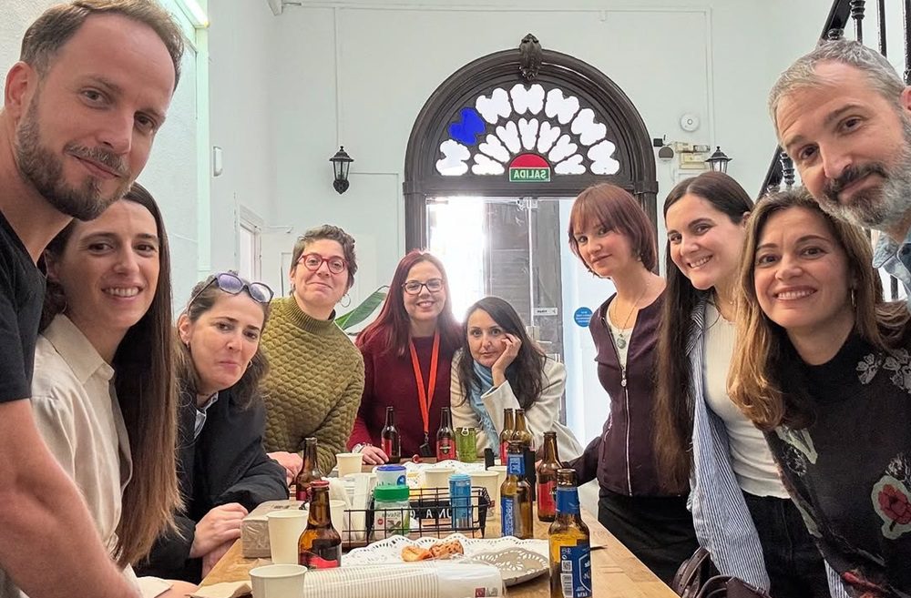 Grupo de coworkers compartiendo un aperitivo y cervezas en la zona común del coworking.