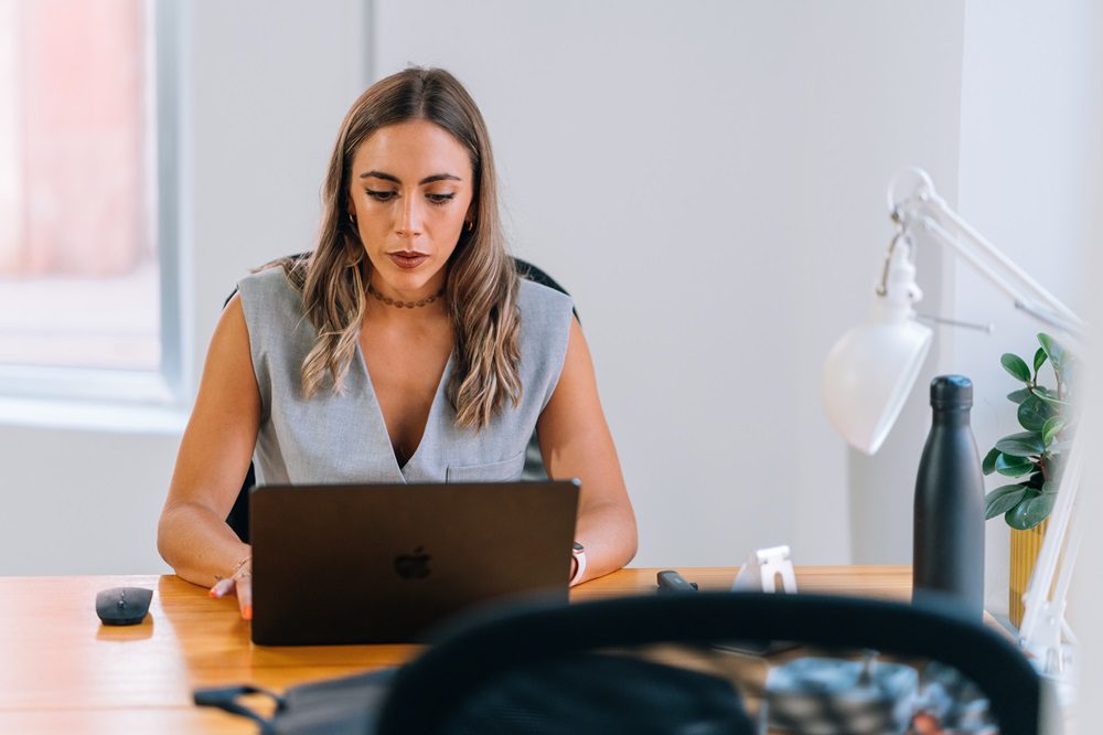 Persona utilizando un temporizador de cocina junto a un portátil para aplicar la técnica Pomodoro mientras trabaja.
