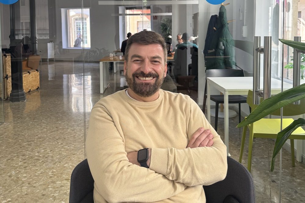 Dos profesionales conversan en un espacio de coworking moderno y luminoso con mesas compartidas y portátiles.