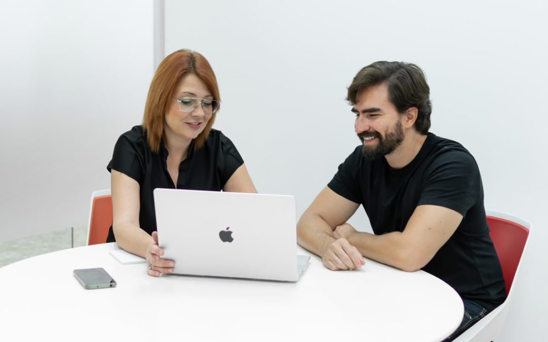 Dos profesionales reunidos con un portátil en una sala privada de trabajo