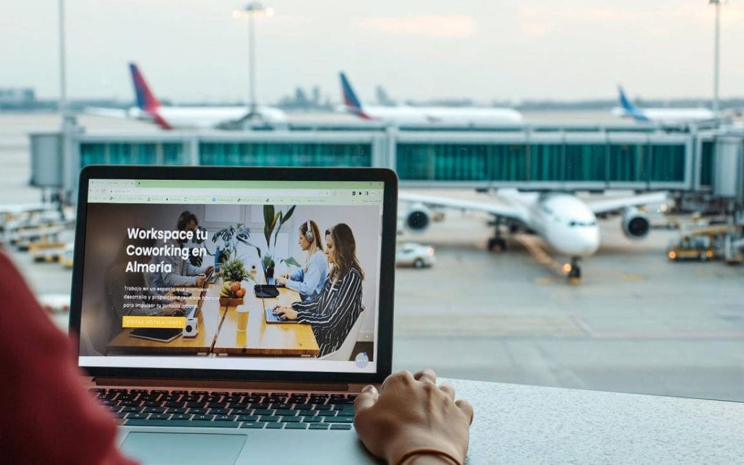 Profesional usando un portátil en el aeropuerto mientras consulta Workspace Coworking Almería para trabajar durante su visita a la ciudad.